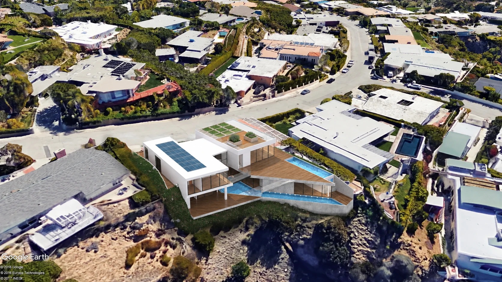 Aerial view of the house turning toward the ocean within its hillside neighborhood
