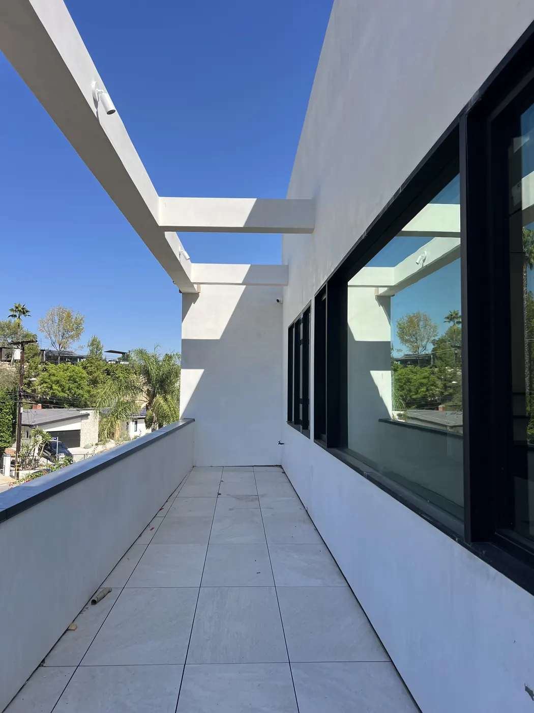Tall glazed passage between white walls and overhead framing