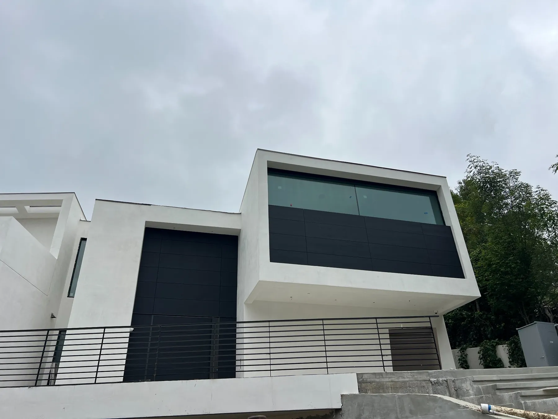 Close view of the projecting upper volume with charcoal panels, broad glazing and white frame