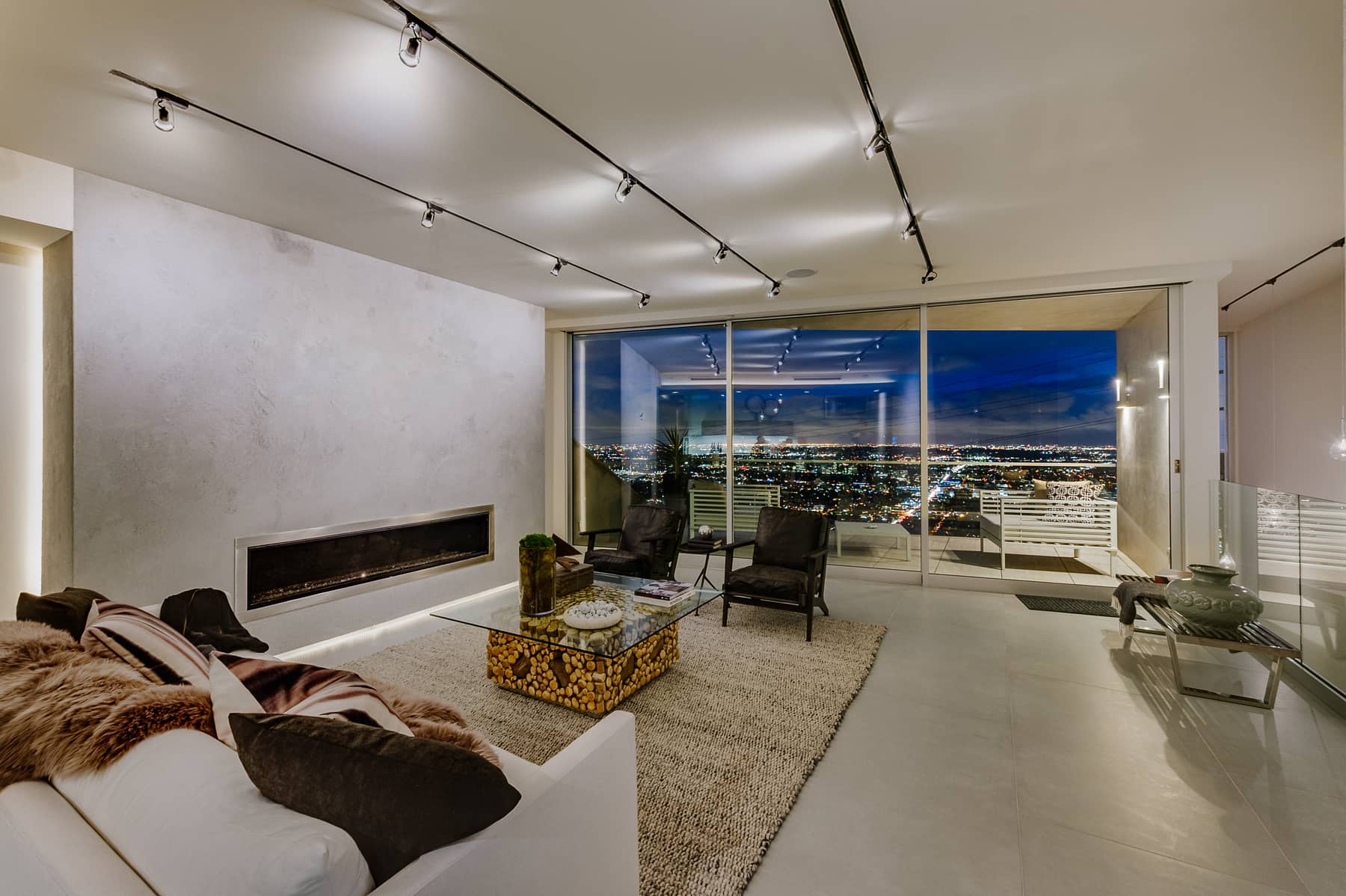 Living room opening through full-height glass toward the Los Angeles night view