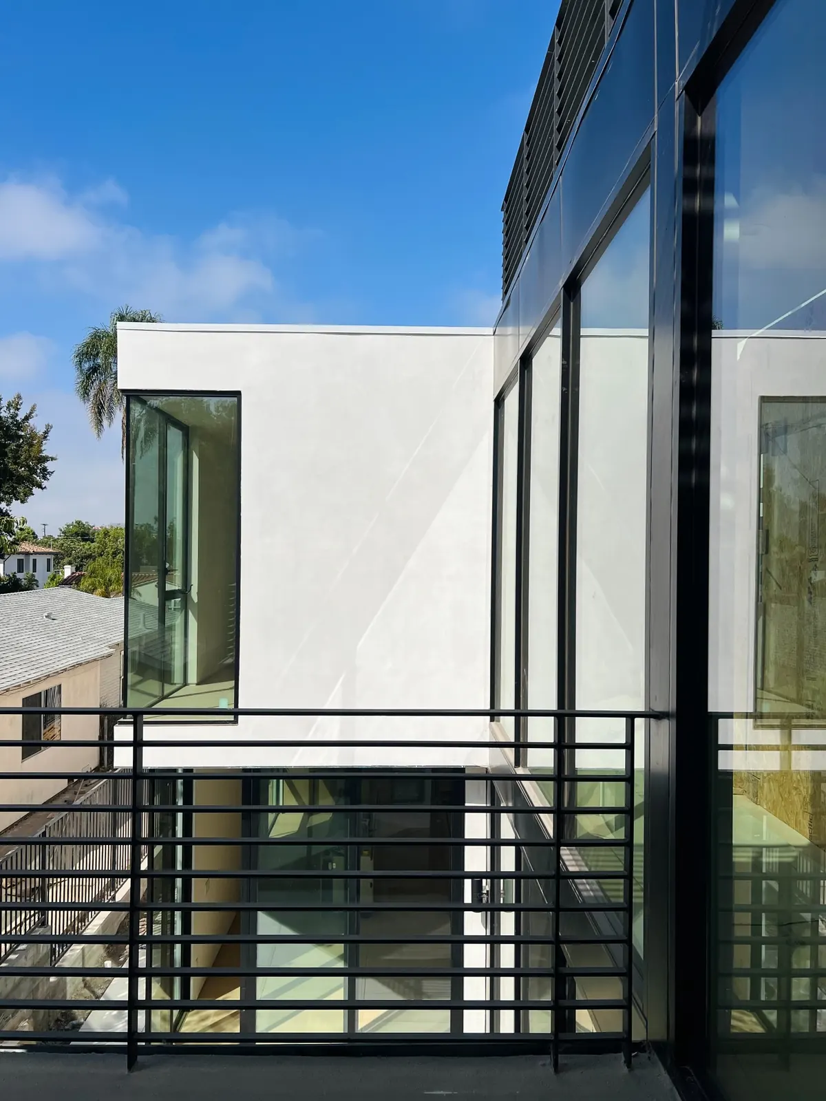 View across the black terrace railing toward the white courtyard volume and glazing