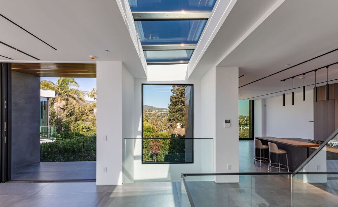 Skylit central interior with open kitchen and glass railing